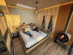 a man and woman sitting on a bed with their laptops at Tiny house, comfort and peace facing Chimborazo in Riobamba