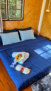 a blue bed with two plates and towels on it at ริมแควโฮมสเตย์ กาญจนบุรี in Ban Pong Pat