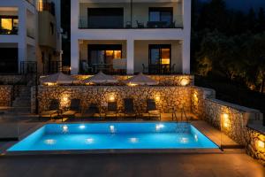 a swimming pool in front of a building at night at Charisma apartments in Nikiana