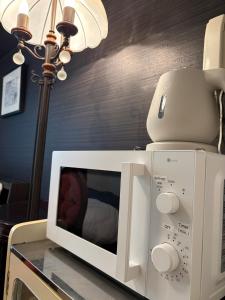 a white microwave on a table next to a lamp at Hachioji House 102 Apartment in Hachioji