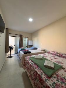 a hotel room with two beds and a television at Pousada Nascer da Lua in São Thomé das Letras