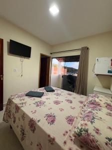 a bedroom with a bed with a floral bedspread at Pousada Nascer da Lua in São Thomé das Letras