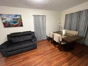 a living room with a black leather couch and a table at Spacious 3BR Niagara Stay + Backyard in Niagara Falls