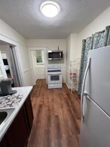 a kitchen with a white refrigerator and wooden floors at Spacious 3BR Niagara Stay + Backyard in Niagara Falls