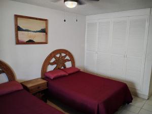 a bedroom with two beds with red sheets at CONDOMINIO SÁBALO VISTA in Mazatlán