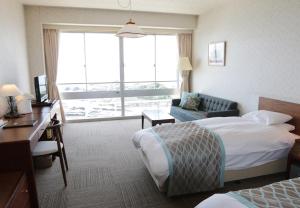 a hotel room with a bed and a couch and a window at Shiosai Resort Kamogawa in Kamogawa