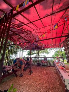 a group of people sitting at tables under a red tent at Lainkalogos Glamping in Rabia
