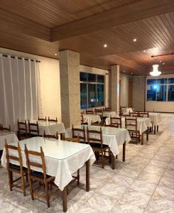a dining room with white tables and chairs at Hotel Nacional Coral in Lages