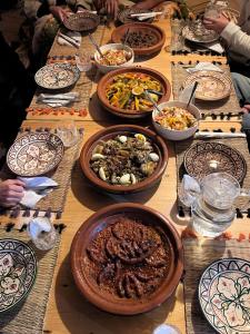 a table full of plates and bowls of food at Emallayan Hostel in Imsouane