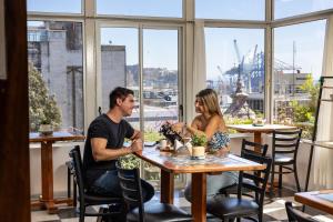 a man and woman sitting at a table in a restaurant at AYCA La Flora Hotel Boutique in Valparaíso