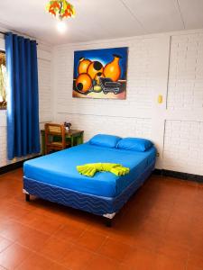 a bedroom with a blue bed with a painting on the wall at hotel Oasis Managua Experience - HOME in Managua