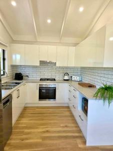a white kitchen with white cabinets and a wooden floor at Cygnet Escape in Cygnet River
