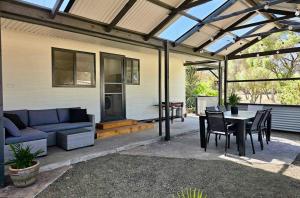 a patio with a blue couch and a table and chairs at Cygnet Escape in Cygnet River
