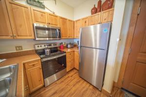 a kitchen with wooden cabinets and a stainless steel refrigerator at Expedition Station 8554 by SummitCove Lodging in Colorado in Keystone