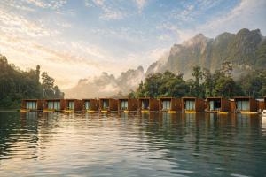 a row of huts on the water with mountains in the background at 360 issara Floating Resort in Ban Chieo Ko +33 photos
