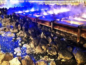 a group of rocks next to a river with blue lights at 湯畑源泉宮崎館 in Kusatsu