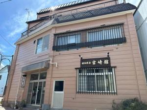 a pink building with a sign on the side of it at 湯畑源泉宮崎館 in Kusatsu