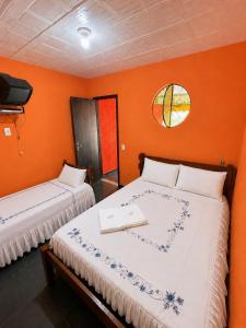 two beds in a room with orange walls and a window at Pousada Quinta de Areal in Areal