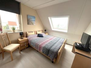 a bedroom with a bed and a tv and two windows at Park De Markol Tureluur 13 in Lemmer