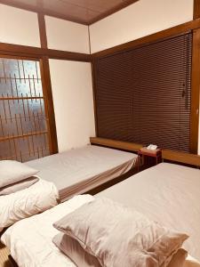 a bedroom with two beds and a window at IPPONMATSU Private Villa - 宮崎の古民家一棟貸し 一本松 in Miyazaki