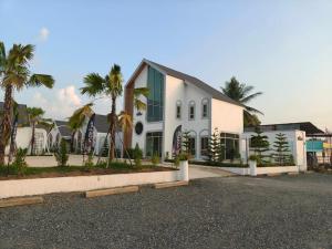 a white house with palm trees in front of it at นนท์ ณ in Ban Non Makhuk