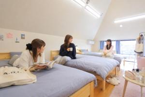 three girls sitting on beds in a room at Hostel FIVE ホステルファイブ in Kochi