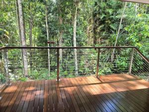 a wooden deck with a view of a forest at Rainforest Escape moments from Waterfall in Kuranda