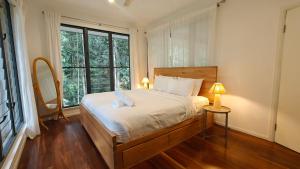 a bedroom with a bed and a large window at Rainforest Escape moments from Waterfall in Kuranda