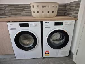 two washing machines in a laundry room with a counter at Rainforest Escape moments from Waterfall in Kuranda