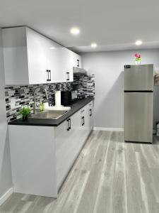 a kitchen with white cabinets and a stainless steel refrigerator at Spacious Entire Basement Suite with Free Parking Self Check In in Winnipeg