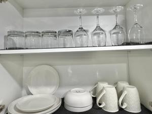 a shelf with glasses and plates and cups on it at Spacious Entire Basement Suite with Free Parking Self Check In in Winnipeg