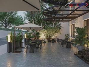 eine Terrasse mit Tischen, Stühlen und einem Sonnenschirm in der Unterkunft Halora Ten Lua Hotel in Ho-Chi-Minh-Stadt