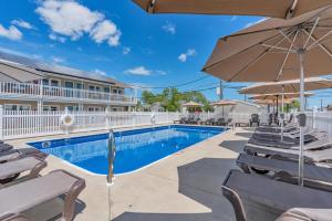 a swimming pool with chairs and an umbrella at Surfside Motel in Point Pleasant Beach