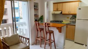 a kitchen with a white refrigerator and wooden stools at Lindo en el rodadero in Gaira