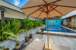 an umbrella sitting on a deck next to a swimming pool at Divine Divers Gili Meno in Gili Meno