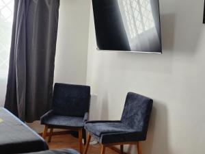 two blue chairs sitting next to a wall at 25 Habitación doble cama in Miravalle