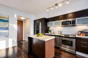 a kitchen with stainless steel appliances and wooden cabinets at Altitude Suites on Yonge - Downtown Toronto Short Walk to SickKids, TMU & Eaton Centre in Toronto