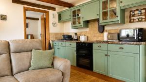 a kitchen with green cabinets and a couch at 1 Bed in Winskill oc-c36298 in Little Salkeld