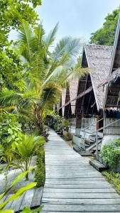 a wooden path leading to a resort with palm trees at Warahnus dive homestay in Kri