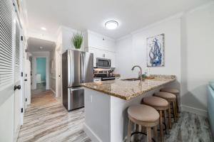 a kitchen with a sink and a counter with stools at BeachFront, Bottom Level Condo at Tradewinds in Orange Beach
