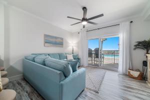 a living room with a blue couch and a ceiling fan at BeachFront, Bottom Level Condo at Tradewinds in Orange Beach +2 photos