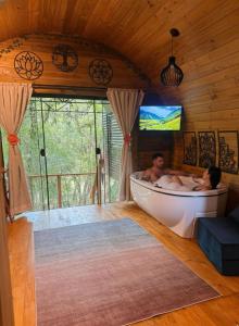 two men in a bath tub in a room with a tv at Cabana Rota do Vinho in São Roque