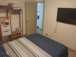 a bedroom with a bed and a flat screen tv at Apto terreo bem arejado e iluminado in Gravataí