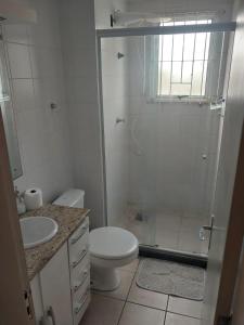 a bathroom with a shower and a toilet and a sink at Apto terreo bem arejado e iluminado in Gravataí
