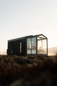 a black house with large windows on a field at Tiny Glass lodge in Selfoss