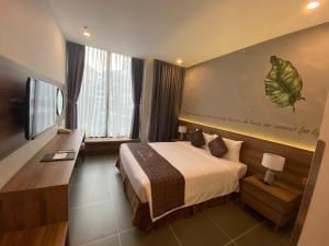 a bedroom with a bed and a desk and a television at Thanh Long Hotel - Bach Dang in Ho Chi Minh City