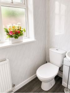 a bathroom with a toilet and a window with flowers at Cozy Corner in Wolverhampton City Centre in Wolverhampton
