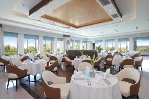 a restaurant with white tables and chairs and windows at Castle Bayview Resort & Spa in Kampot