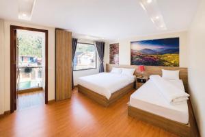 a bedroom with two beds and a large window at Cloud House Sapa in Sapa