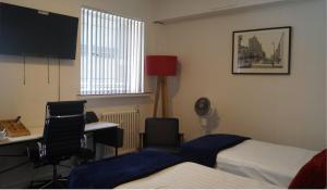 a hotel room with two beds and a desk and a television at YMCA Hotel in London